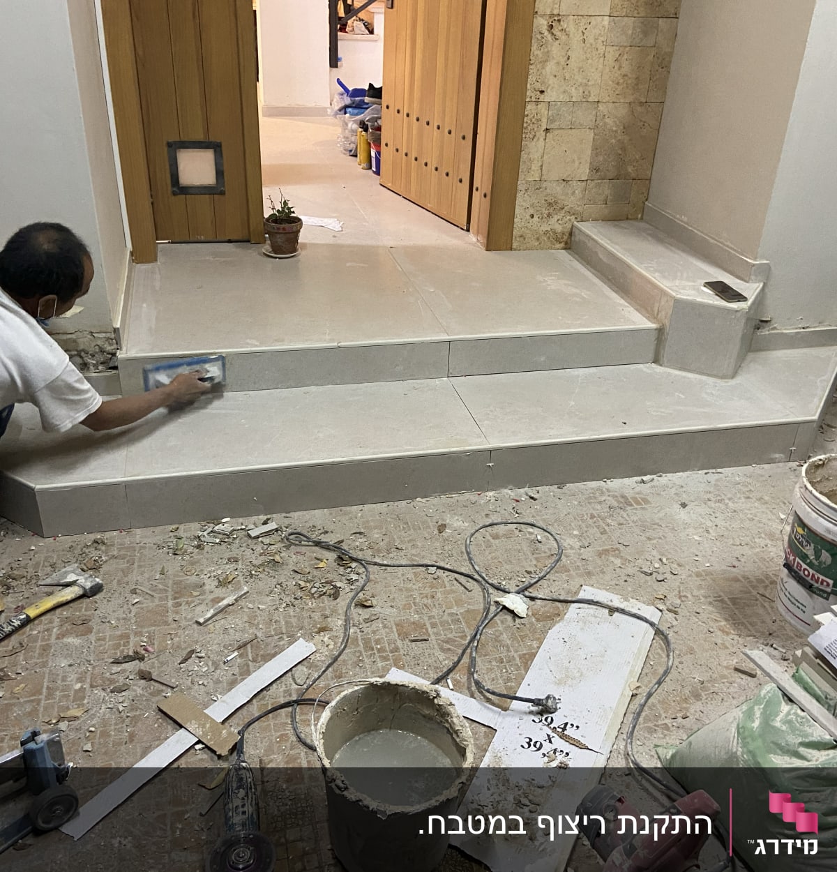 עובד משפץ מדרגות עם כלי עבודה וחומרי בניין